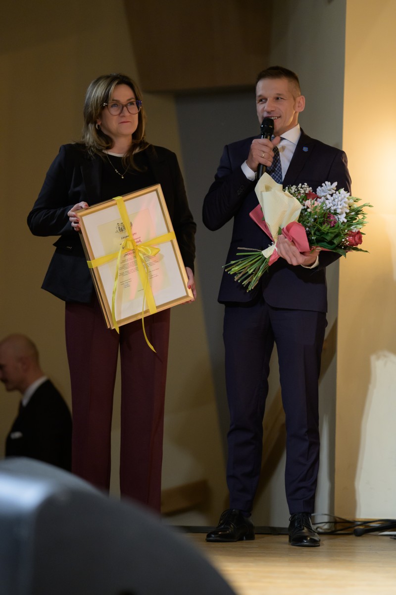 Kobieta i mężczyzna stojący na scenie. Mężczyzna przemawia