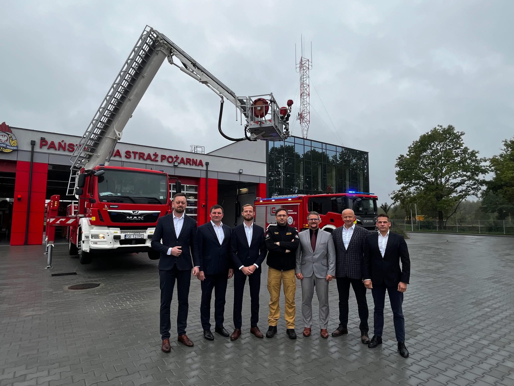 7 mężczyzn pozujacych do zdjęcia przed budynkiem JRG w Bieruniu