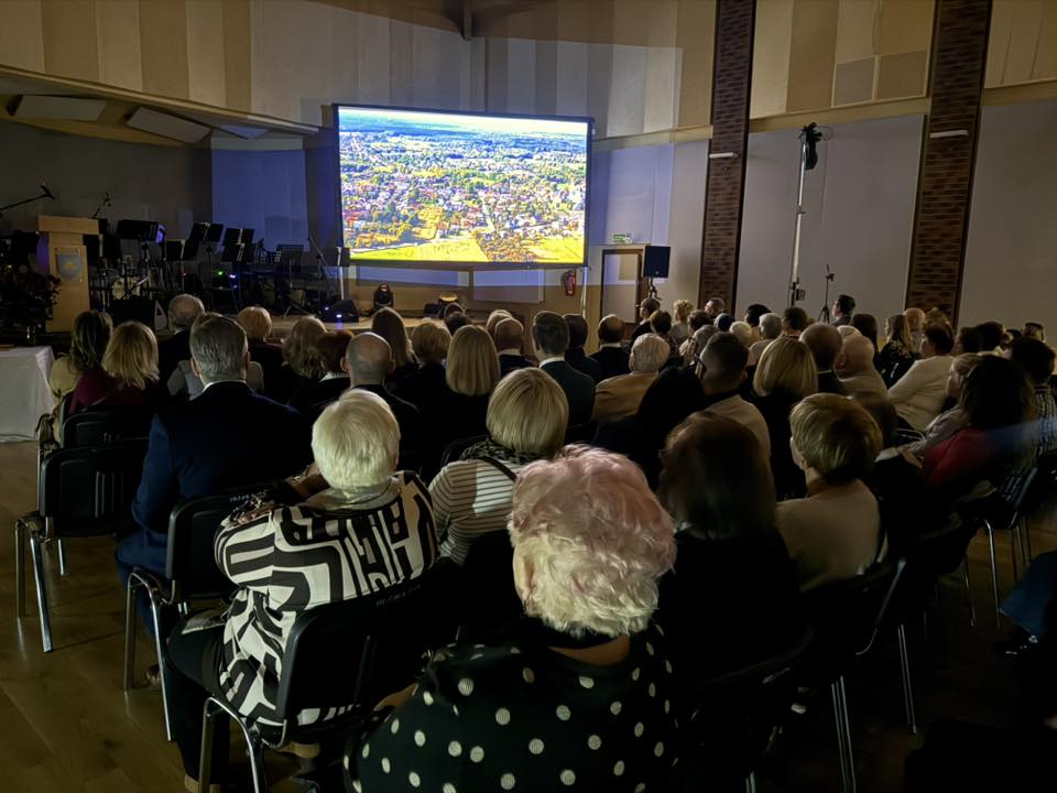 Osoby siedzące w sali i oglądające film. W oddali ekran filmoy