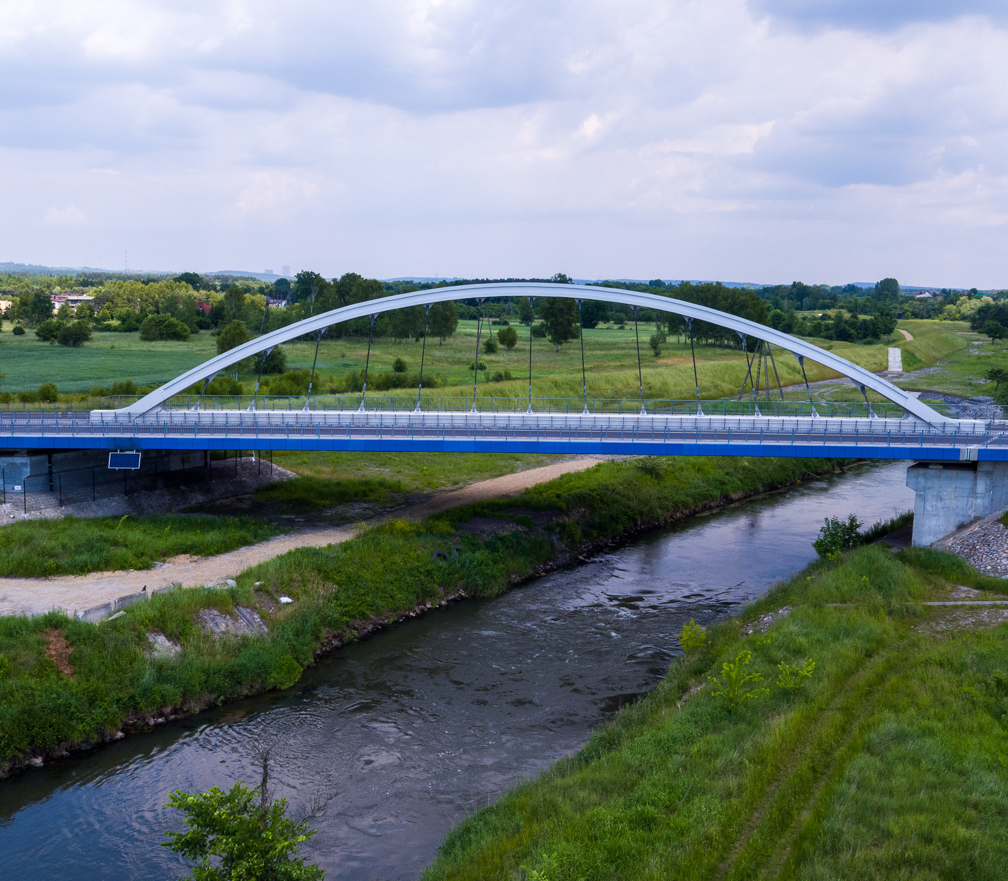 Rzeka a nad nią most. Dookoła rozległe łąki