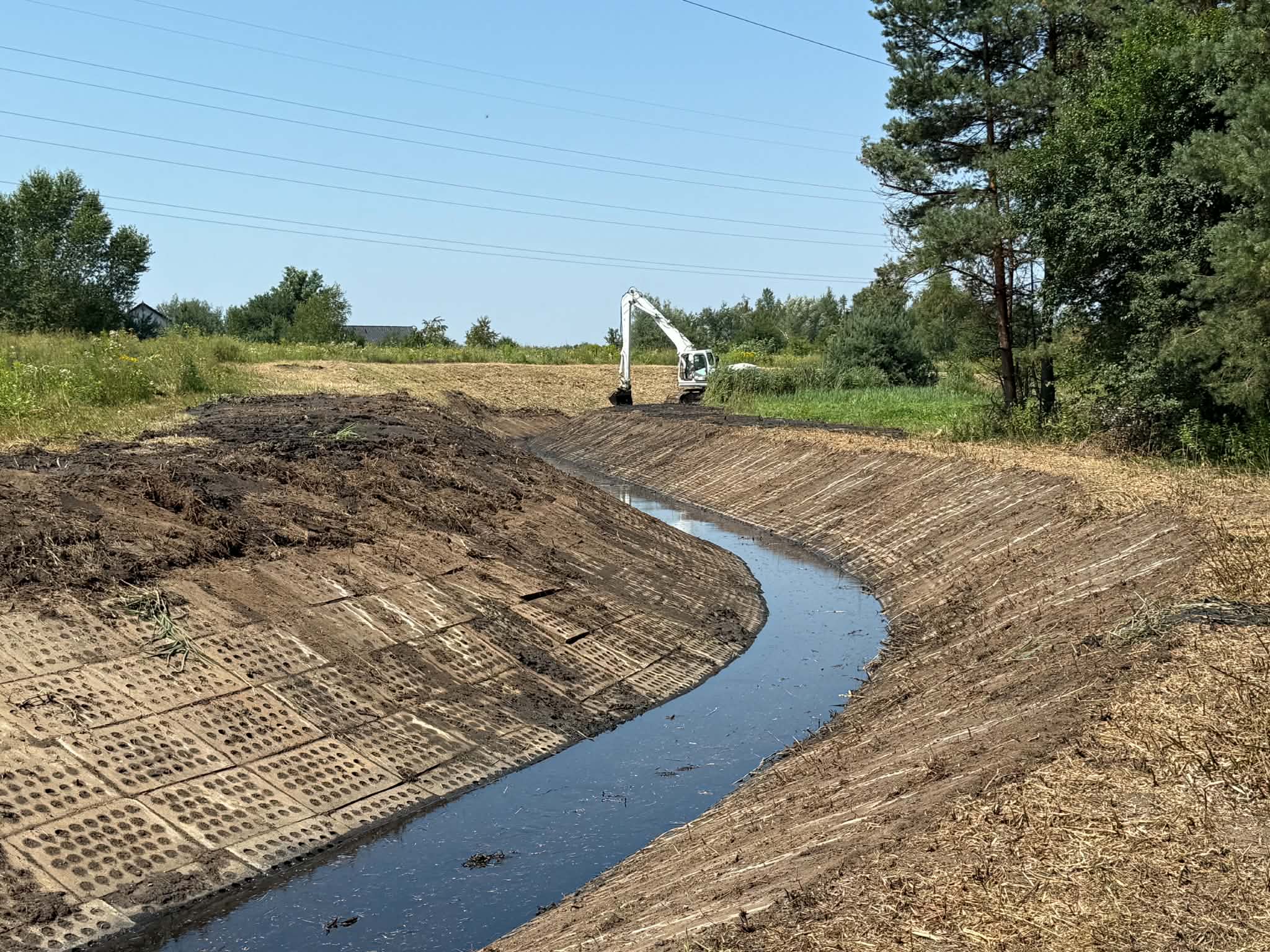 Rów melioracyjny w oddali koparka 