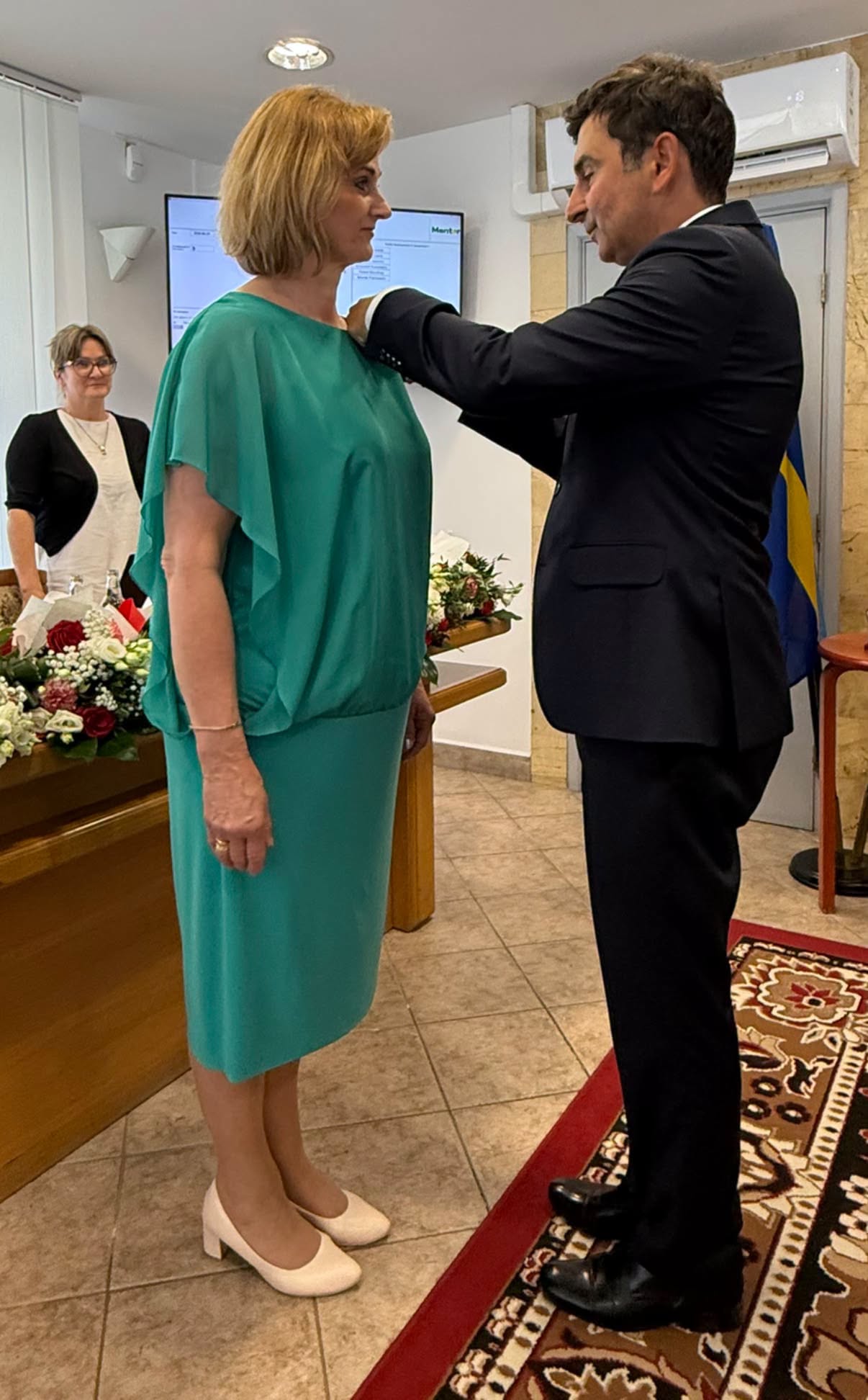 Mężczyzna przypina medal kobiecie. 
