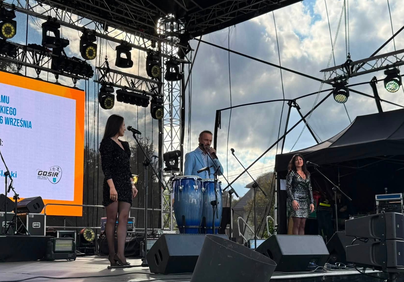 Trzy osoby na scenie plenerowej 