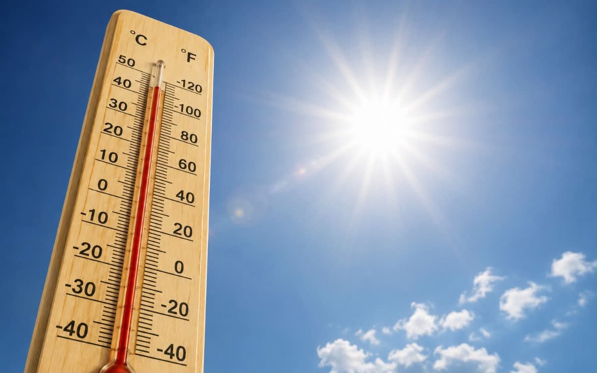 Termomert pokazujący wysoką temperaturę, na tle nieba i słońca
