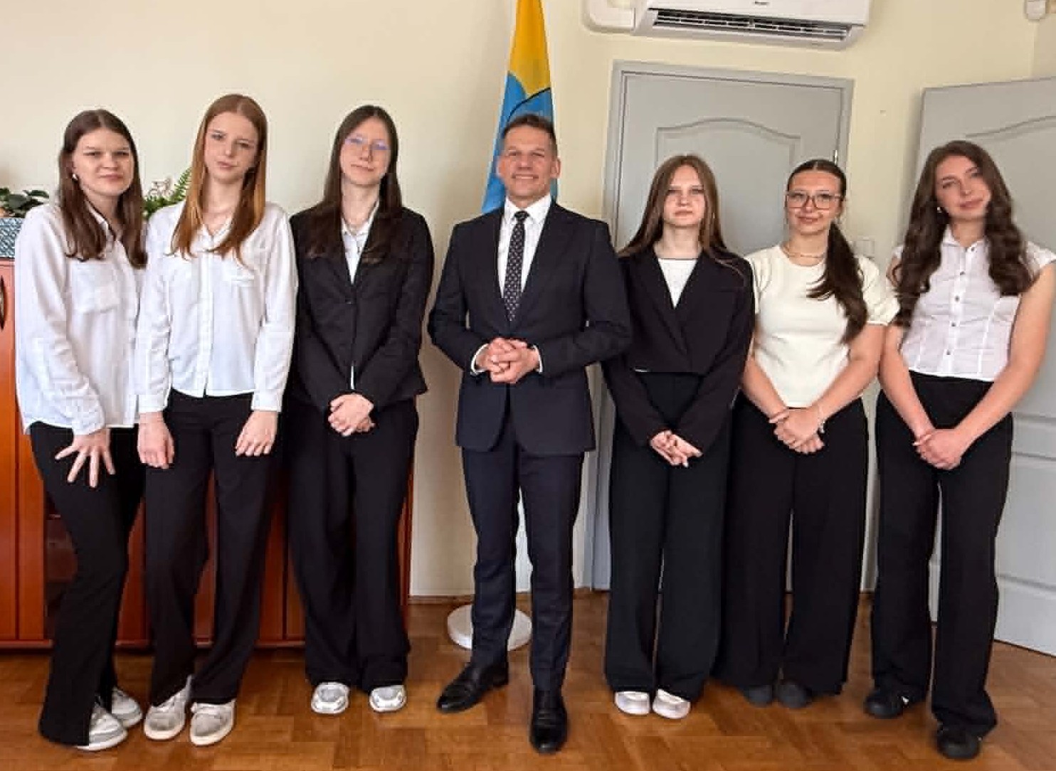 Mężczyzna i sześc dziewcząt pozujących do zdjęcia w pomieszczeniu 