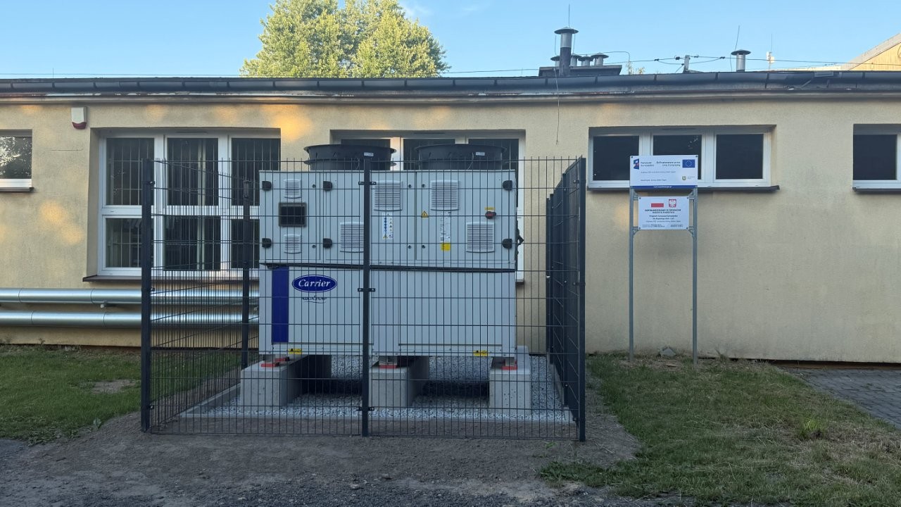 Budynek a przed nim pompa grzewcza 