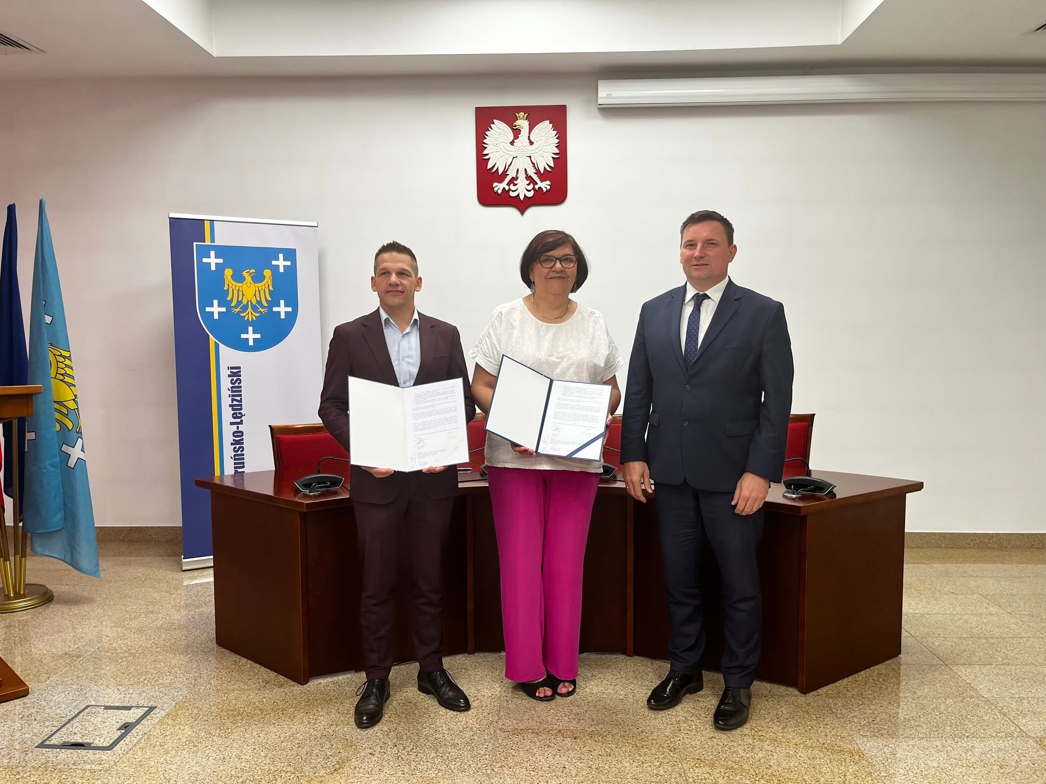 Trzy osoby pozujące do zdjęcia - dwóch mężczyzn i kobieta 
