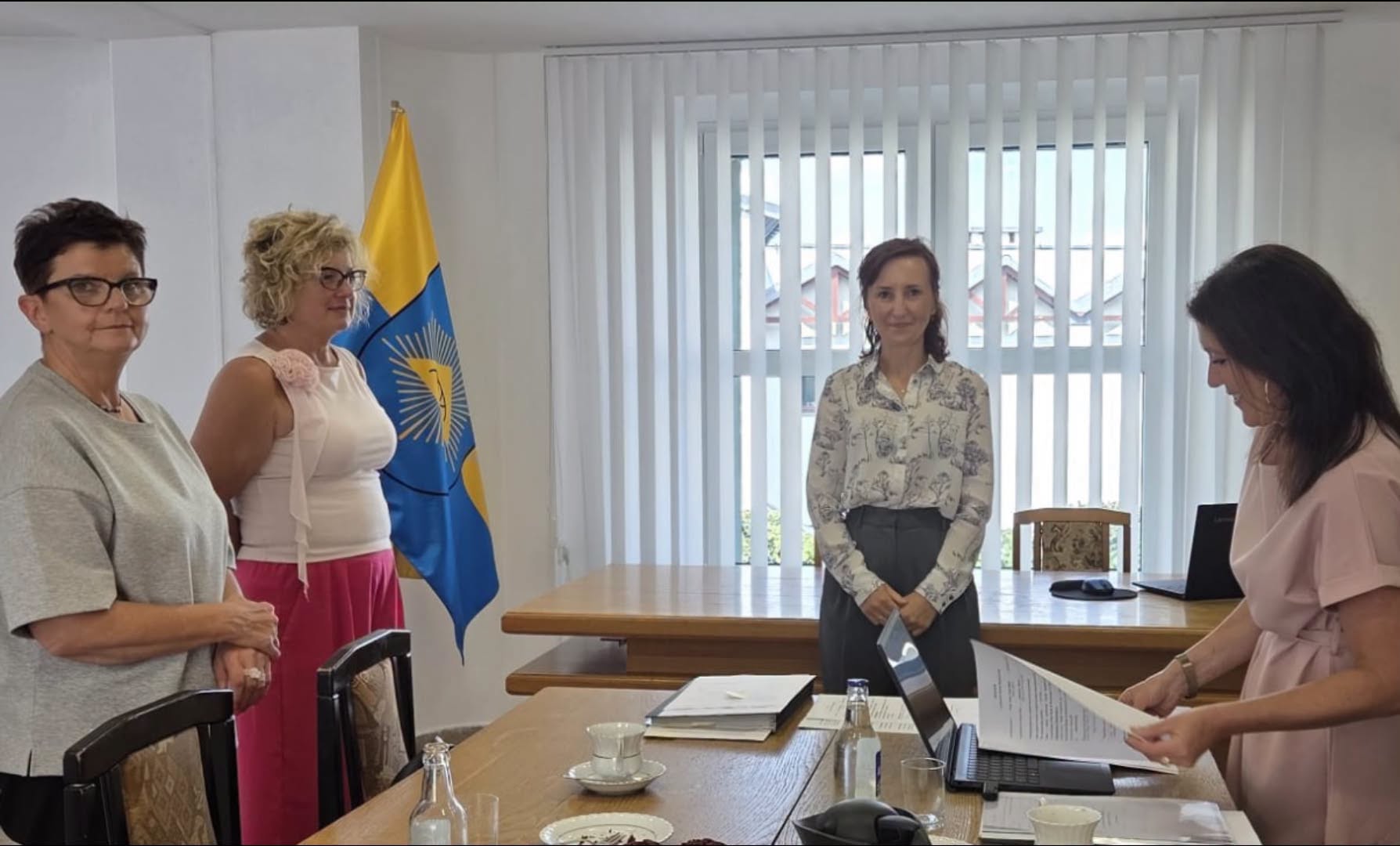 Cztery kobiety stojące w pomieszczzeniu za biurkiem 