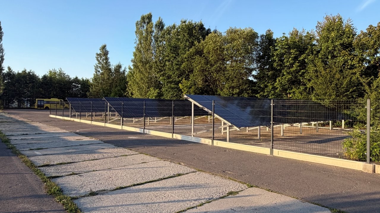 Baterie słoneczne ustawione na łące z ogrodzeniem 