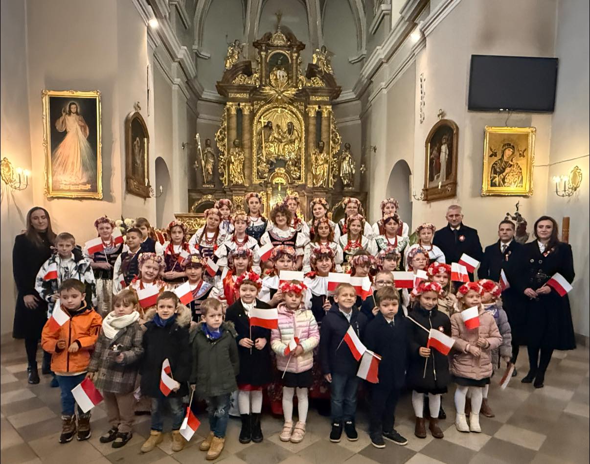 Osoby w strojach ludowych - dzieci i dorosli pozujący do zdjęcia w Kościele, stojąc przy Ołtarzu 