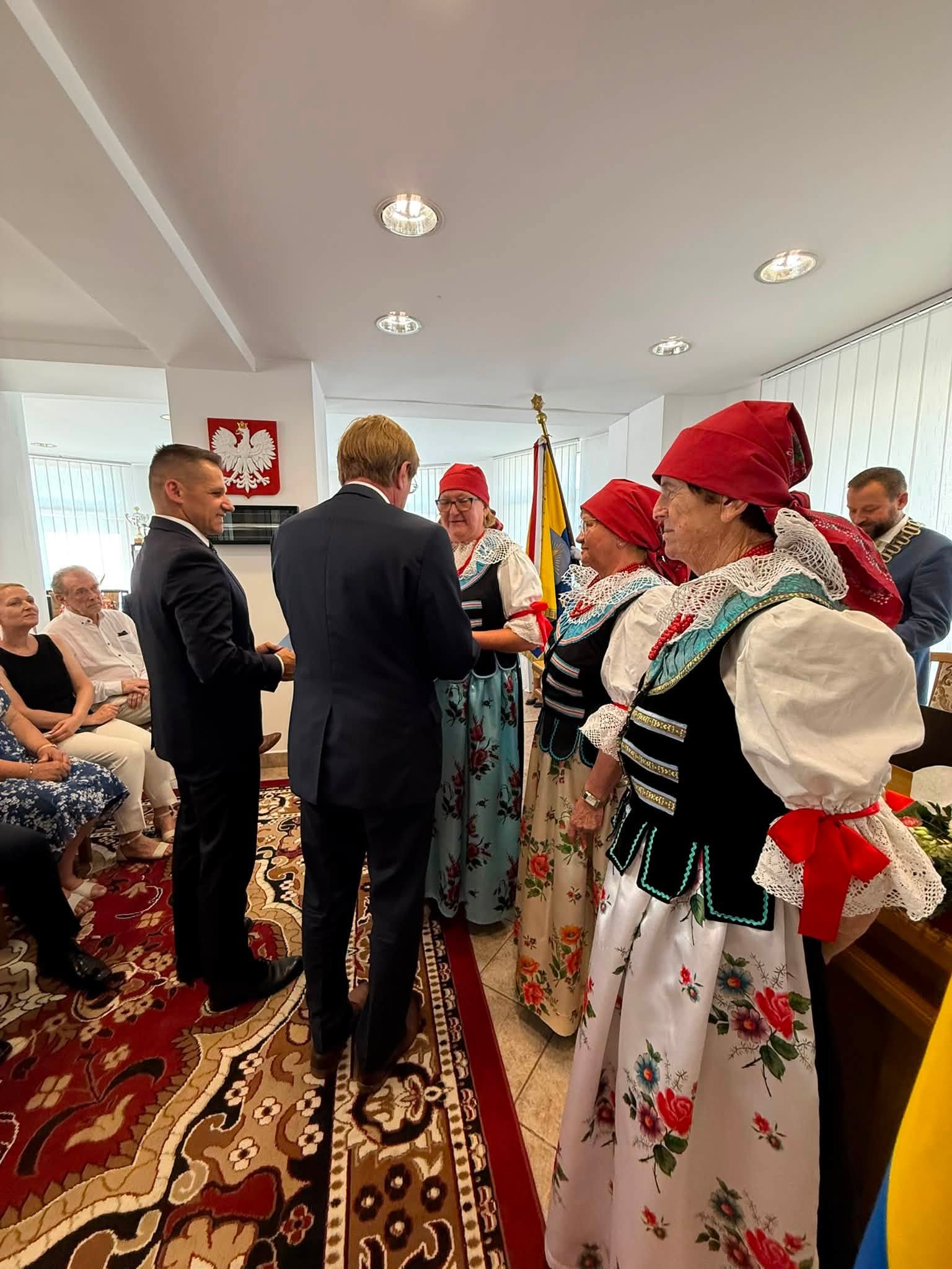 Mężczyźni przyznający odznaczenia paniom w strojach ludowych. 