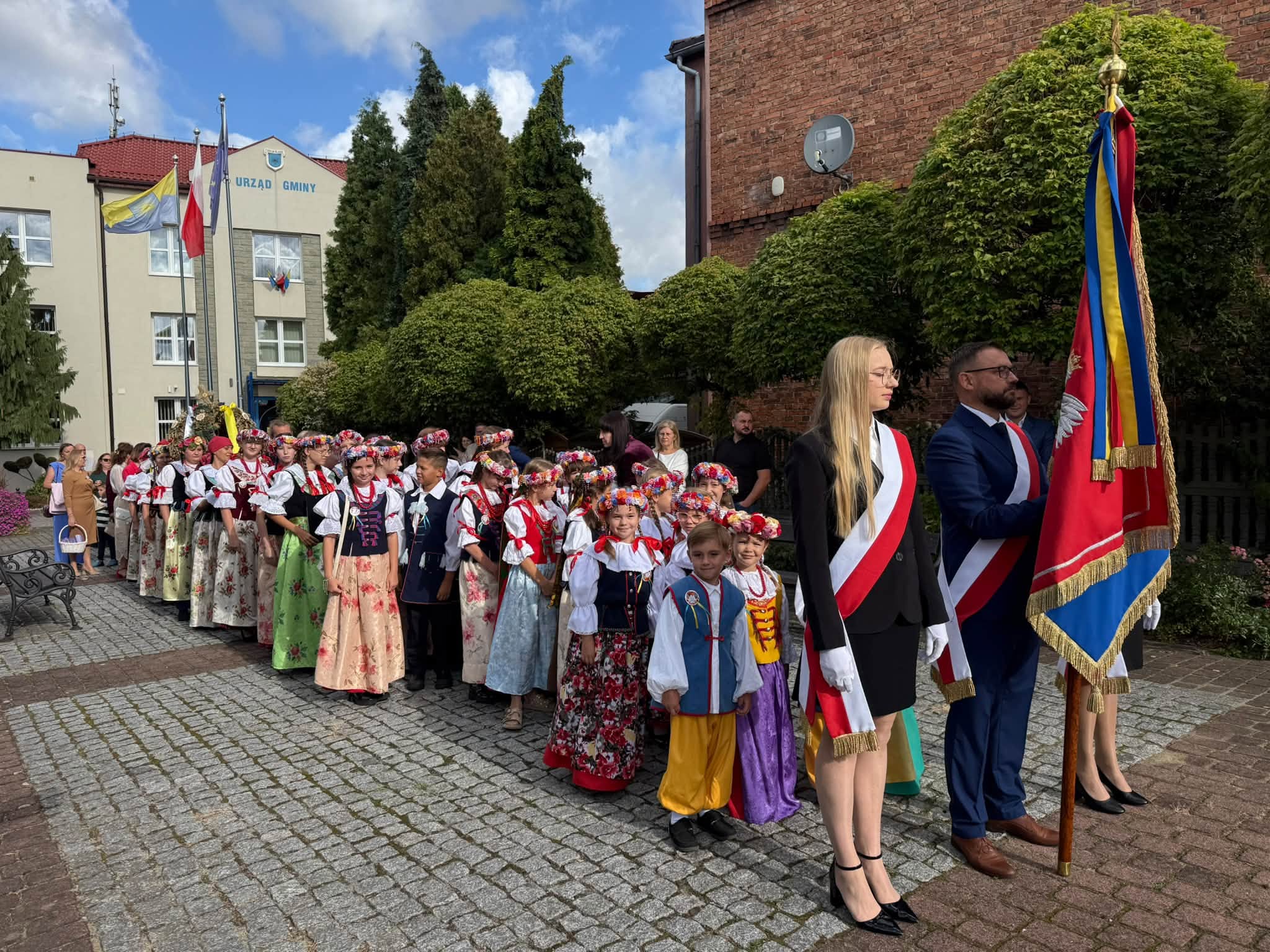 Korowód dożynkowy - dzieci w strojach ludowych, poczet sztandarowy 